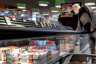 Ein Mann steht an der Tiefkühltheke eines Supermarkts: Die Preise für Produkte wie Fertigpizza könnten bald steigen.