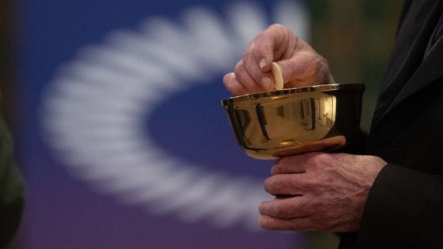 Ein Mitglied der Kirchengemeinde hält während eines Gottesdienstes mit Abendmahl im katholischen Dom St. Ein Mitglied der Kirchengemeinde hält während eines Gottesdienstes mit Abendmahl im katholischen Dom St.