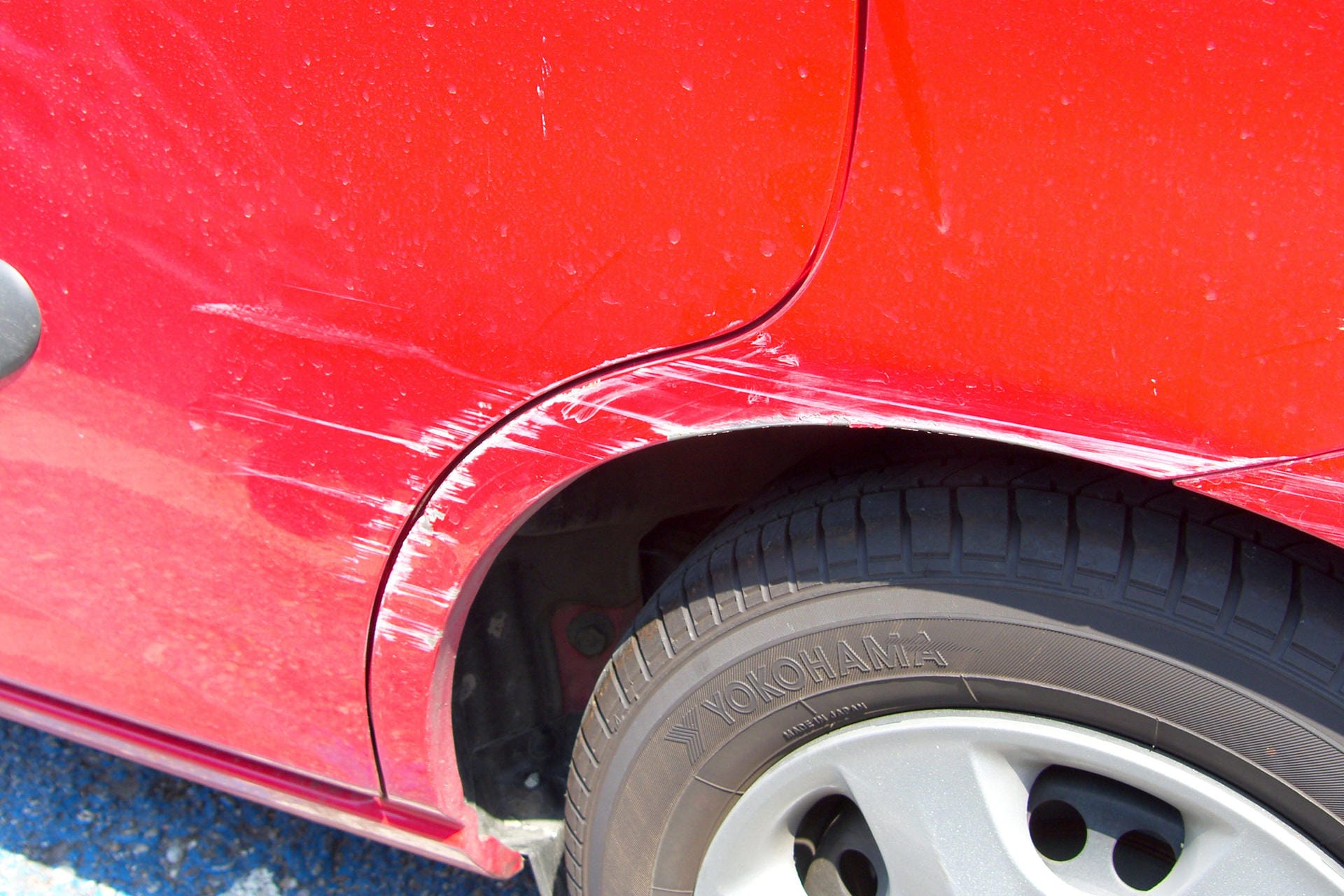 Kratzer an einem roten Auto (Symbolbild): Protokollieren Sie bestehende Schäden am Auto, bevor Sie den Wagen mitnehmen.