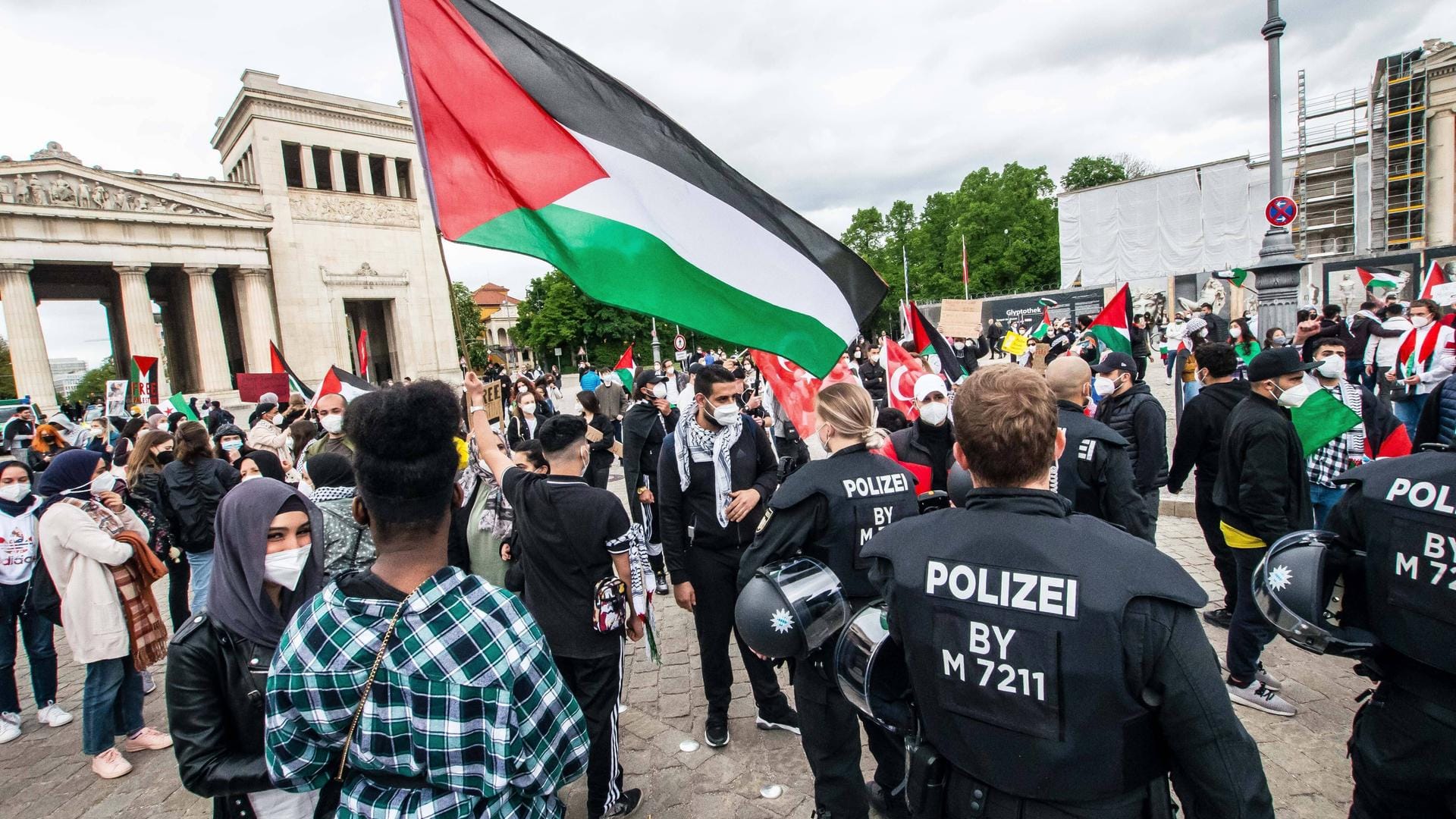 Polizeibeamte suchen am Samstag bei einer Demonstration in München nach antisemitischen Plakaten.