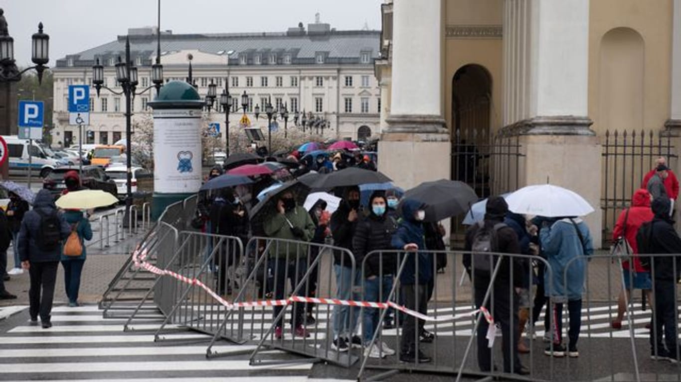 Menschen warten in einer Schlange vor dem Warschauer Rathaus auf ihre Impfung.