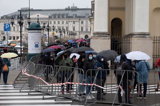 Menschen warten in einer Schlange vor dem Warschauer Rathaus auf ihre Impfung.