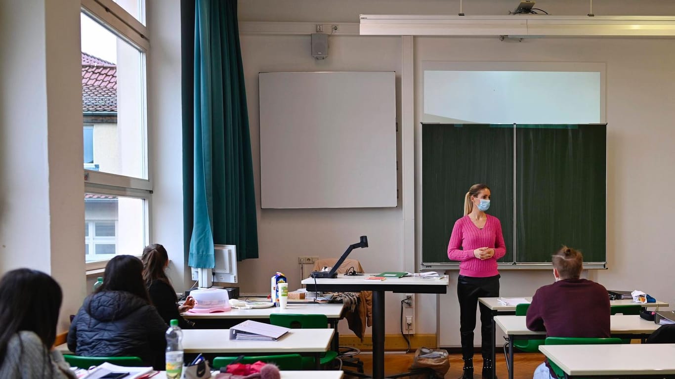 Eine Lehrerin mit Mundschutzmaske im Präsenzunterricht (Symbolbild): In Rheinland-Pfalz sollen die Schüler noch vor den Sommerferien alle in die Schulen zurückkehren.