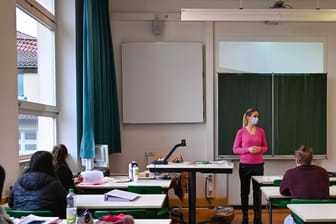 Eine Lehrerin mit Mundschutzmaske im Präsenzunterricht (Symbolbild): In Rheinland-Pfalz sollen die Schüler noch vor den Sommerferien alle in die Schulen zurückkehren.