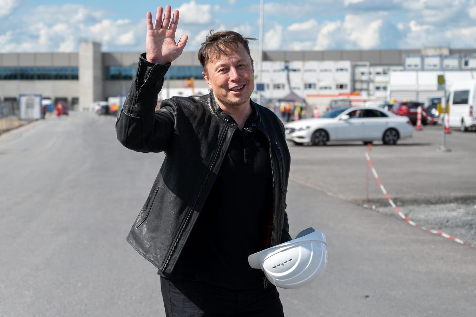 Elon Musk steht auf der Baustelle der Tesla-Fabrik und winkt. Elon Musk steht auf der Baustelle der Tesla-Fabrik und winkt.