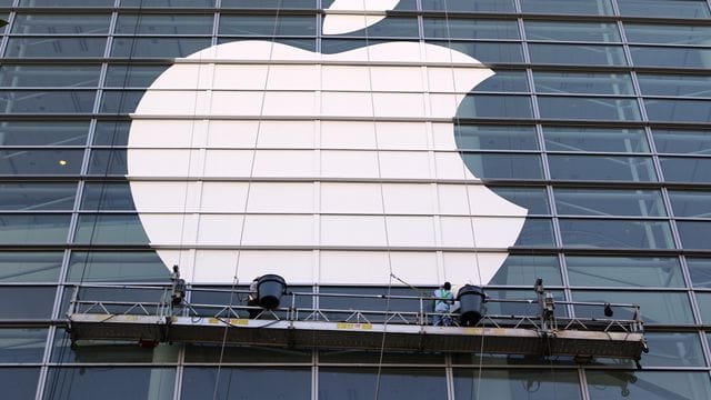 Arbeiter bringen ein übergroßes Apple-Logo an einer Glasfassade in San Francisco an. Arbeiter bringen ein übergroßes Apple-Logo an einer Glasfassade in San Francisco an.
