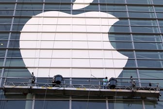 Arbeiter bringen ein übergroßes Apple-Logo an einer Glasfassade in San Francisco an.