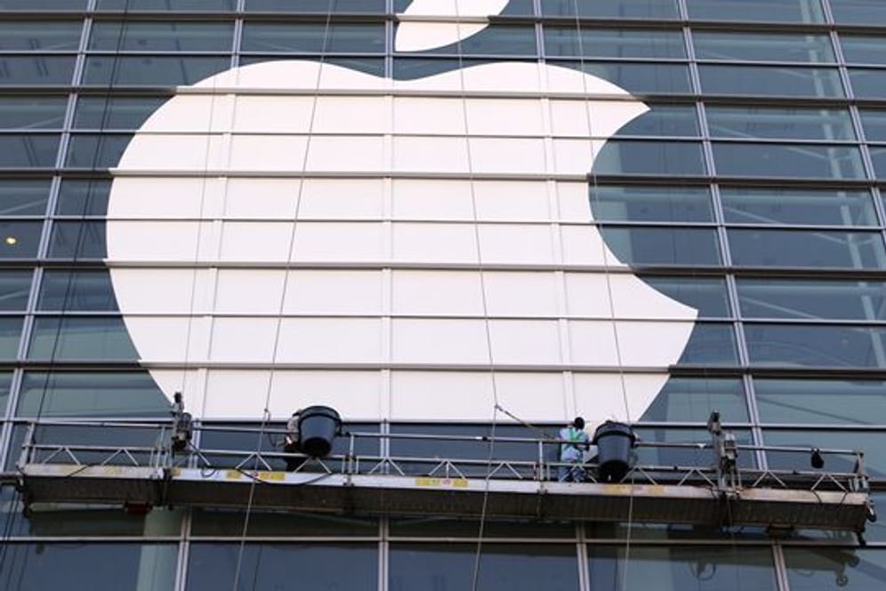 Arbeiter bringen ein übergroßes Apple-Logo an einer Glasfassade in San Francisco an.