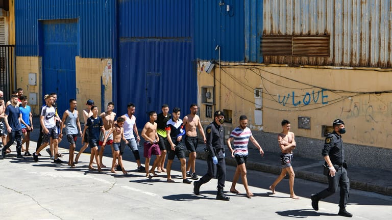 Eine Gruppe junger Migranten wird in Ceuta von Polizisten eskortiert: Sie legten zwei Kilometer schwimmend zurück.
