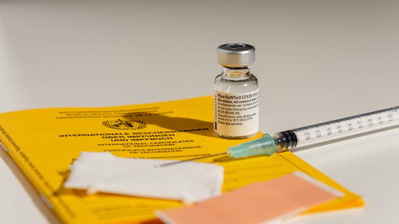 Eine Impfstoffampulle und eine Spritze liegen auf einem Impfpass (Symbolbild): Das aktuelle System zur Vergabe von Impfterminen sorgt für viel Frust bei den Bürgern.