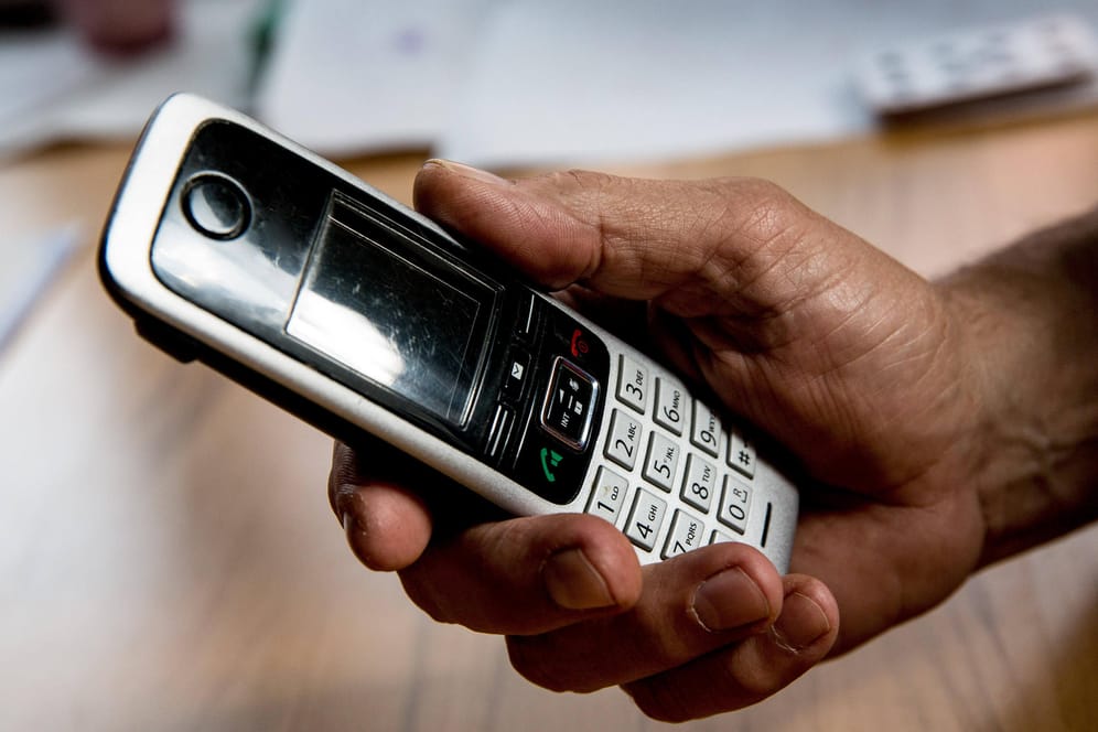 Die Hand eines älteren Menschen hält ein Telefon (Symbolbild): Mit einer Betrugsmasche am Telefon wurde ein Senior in Leverkusen um sein Geld bestohlen.