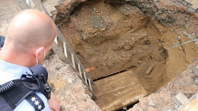 Ein Polizist schaut auf das Loch eines Tunnels, den Unbekannte zur Volksbank gegraben haben. Ein Polizist schaut auf das Loch eines Tunnels, den Unbekannte zur Volksbank gegraben haben.