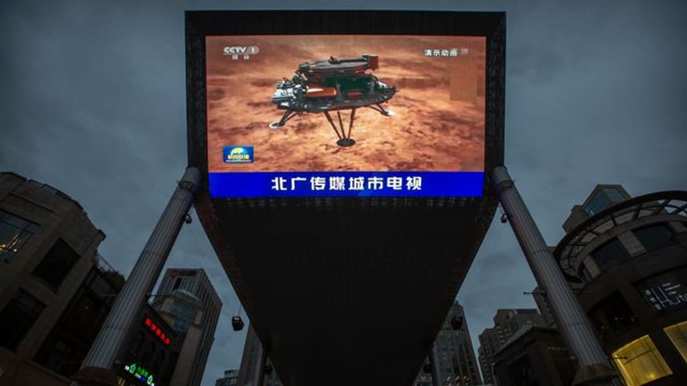 Feiertag für das chinesische Staatsfernsehen: Eine Nachrichtensendung über die erfolgreiche Landung einer Sonde auf dem Mars wird auf einem großen Videobildschirm gezeigt.