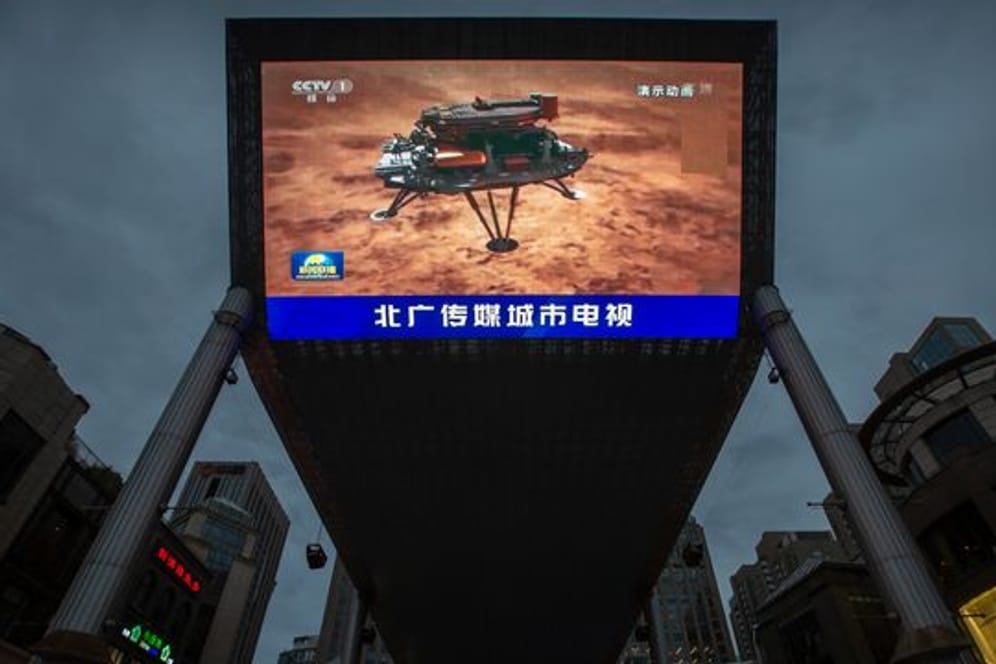 Feiertag für das chinesische Staatsfernsehen: Eine Nachrichtensendung über die erfolgreiche Landung einer Sonde auf dem Mars wird auf einem großen Videobildschirm gezeigt.