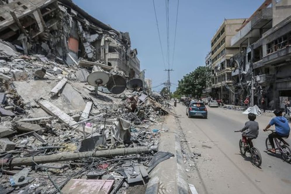 Palästinenser fahren an Gebäuden in Gaza vorbei, die durch israelische Luftangriffe zerstört wurden.