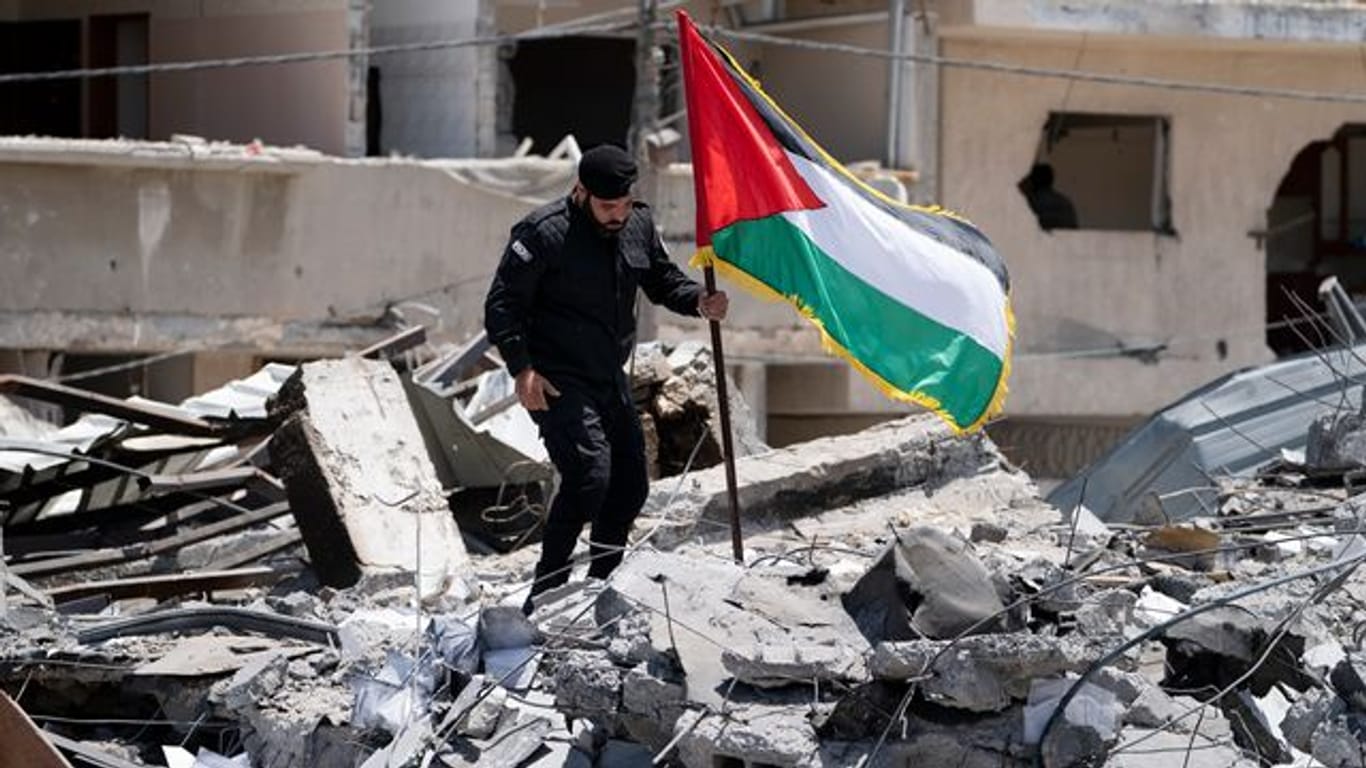Ein Polizist der Hamas entfernt eine palästinensische Fahne von einem Trümmerhaufen eines Bahnhofsgebäudes, das bei Luftangriffen zerstört worden war.