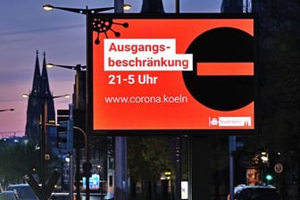 Eine Anzeigetafel in Köln weist Ende April auf die Ausgangsbeschränkung zwischen 21:00 und 05:00 Uhr hin.