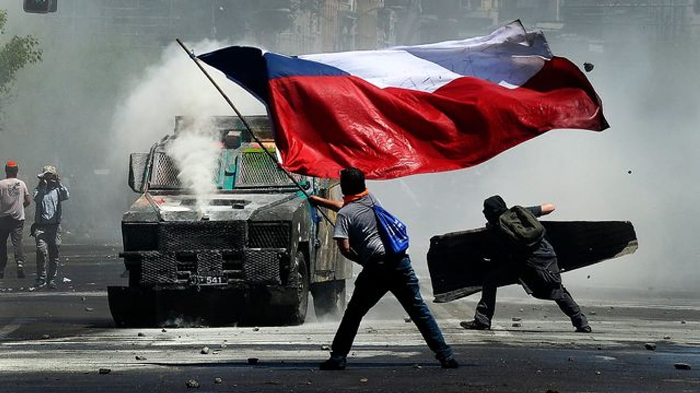 Flagge und Wasserwerfer: Momentaufnahme eines Protests in Chile gegen soziale Ungleichheit und die Regierung.