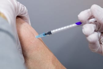 Ein Mann wird von einer medizinischen Fachkraft in einem Impfzentrum gegen das Coronavirus geimpft.