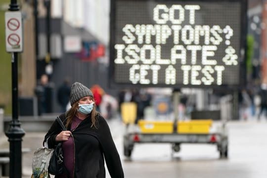 Eine Anzeigetafel erinnert in Großbritannien an das richtige Verhalten beim Auftreten von Corona-Symptomen.