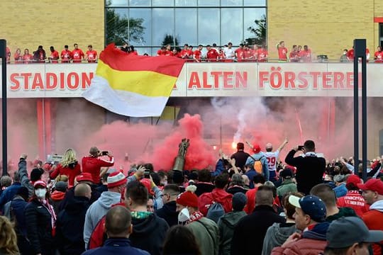 Fans von Union feiern vor dem Balkon, auf dem die Mannschaft steht, die starke Saison ihrer Mannschaft.