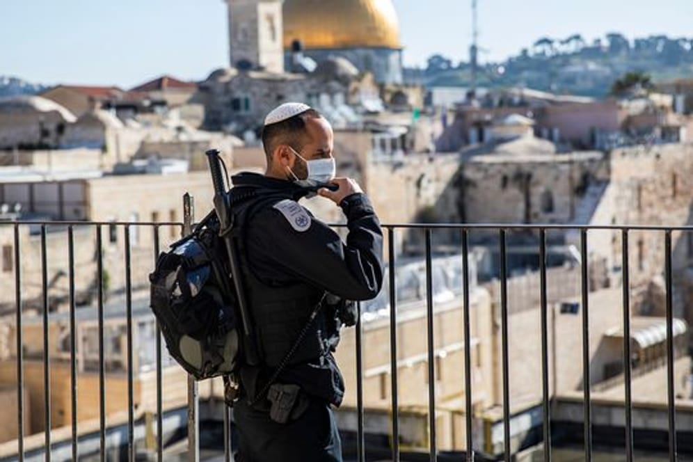Ein israelischer Polizist mit Mundschutz steht in der Altstadt Wache.