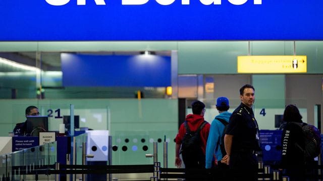 Grenzbeamte stehen am Flughafen Heathrow in London unter einem Schild mit der Aufschrift "UK Border". Grenzbeamte stehen am Flughafen Heathrow in London unter einem Schild mit der Aufschrift "UK Border".