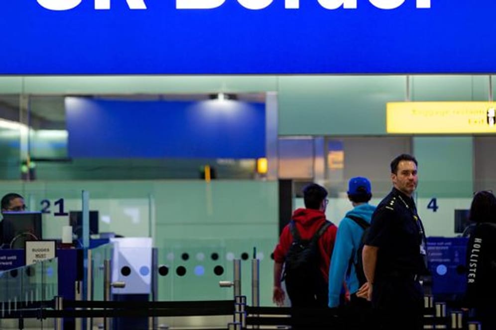 Grenzbeamte stehen am Flughafen Heathrow in London unter einem Schild mit der Aufschrift "UK Border".