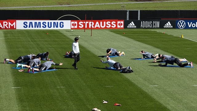 Bundestrainer Joachim Löw (M) steht bei der Erwärmung ohne Ball zwischen den Spielern.