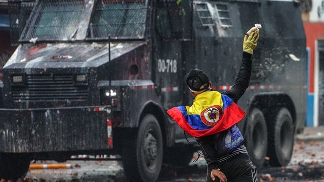 Ein Protestler wirft in einem Außenbezirk von Bogotá einen Farbbeutel auf ein Polizeifahrzeug. Ein Protestler wirft in einem Außenbezirk von Bogotá einen Farbbeutel auf ein Polizeifahrzeug.