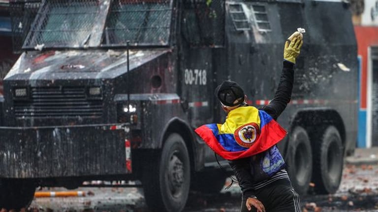 Ein Protestler wirft in einem Außenbezirk von Bogotá einen Farbbeutel auf ein Polizeifahrzeug.