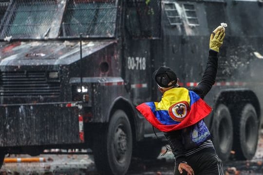 Ein Protestler wirft in einem Außenbezirk von Bogotá einen Farbbeutel auf ein Polizeifahrzeug.