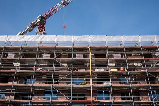Ein Gerüst ist auf einer Baustelle an einem Neubau angebracht
