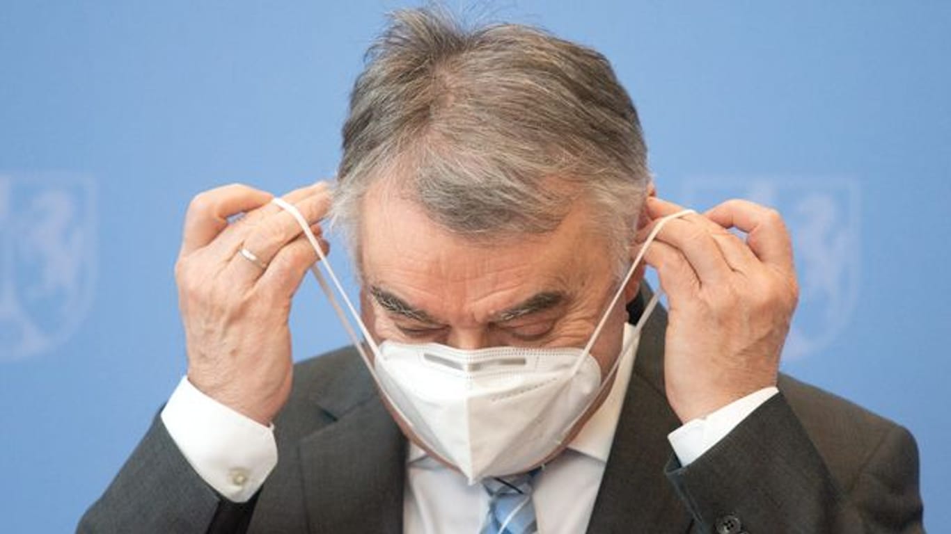 Herbert Reul (CDU) setzt sich einen Mund-Nasen-Schutz auf