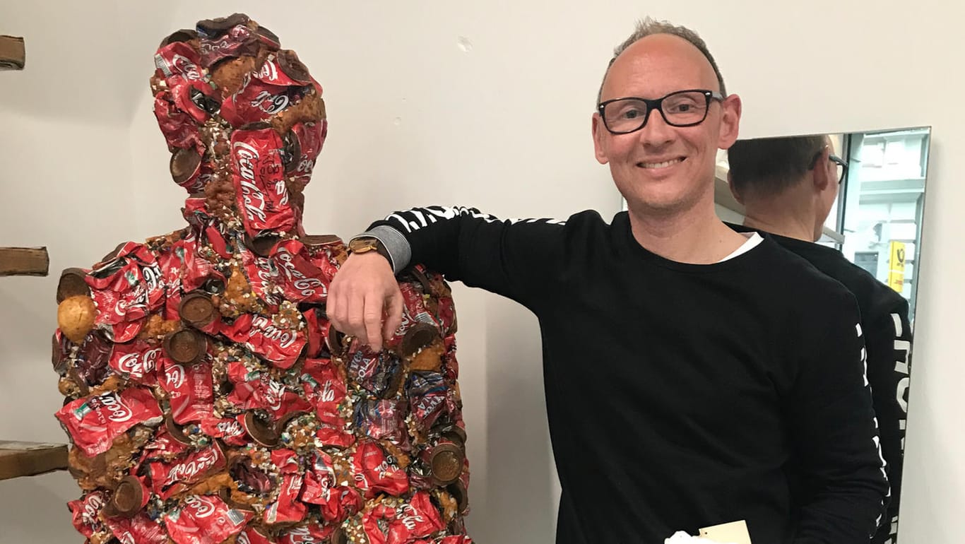 Christian Ohm steht in seinem Laden neben einem Exemplar der original "Trash people" des Kölner Aktionskünstlers HA Schult: Für den Inhaber ist es wichtig, einen Beitrag zu einem nachhaltigen Leben zu leisten.