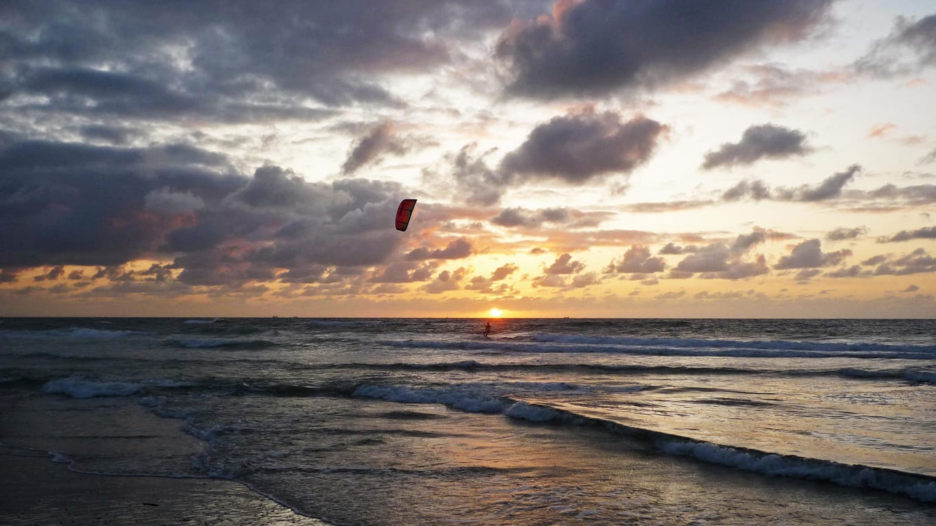 Sonnenuntergang auf Texel: Nur ein einsamer Kitesurfer ist noch in den Wellen.