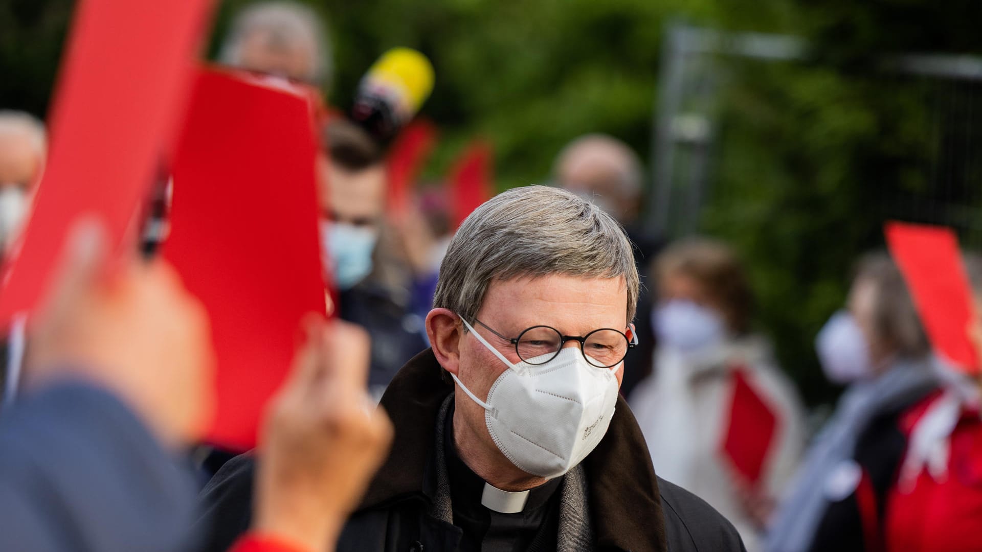 Rainer Maria Woelki geht in Düsseldorf durch einen Spalier aus Gemeindemitgliedern, die ihm die Rote Karte zeigen.