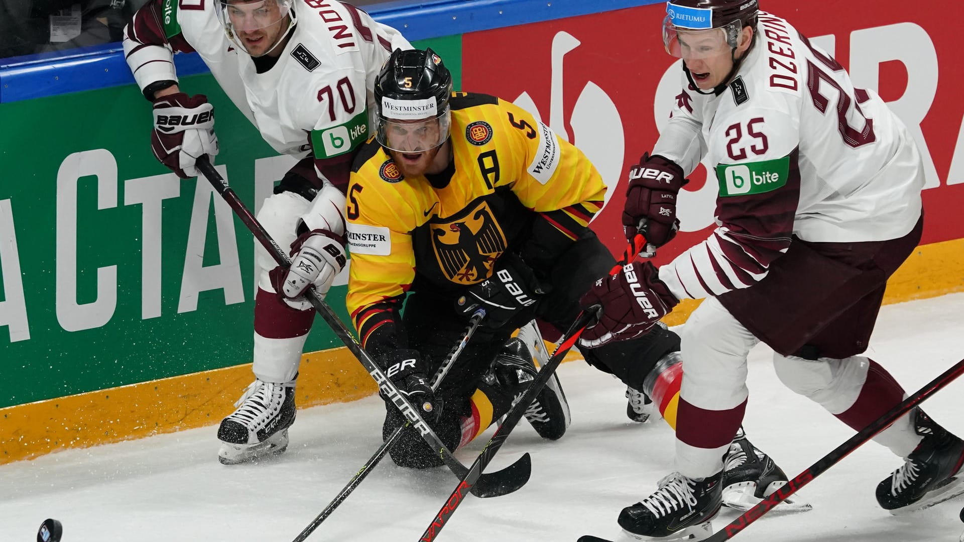 Stellvertretend für eine intensive Partie: Deutschlands Korbinian Holzer (M.) streitet sich mit den Letten Miks Indrasis (l.) und Andris Dzerins um den Puck.