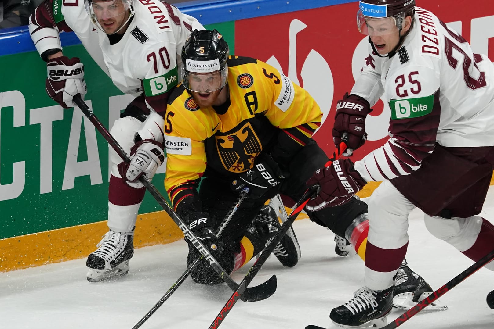 Stellvertretend für eine intensive Partie: Deutschlands Korbinian Holzer (M.) streitet sich mit den Letten Miks Indrasis (l.) und Andris Dzerins um den Puck.