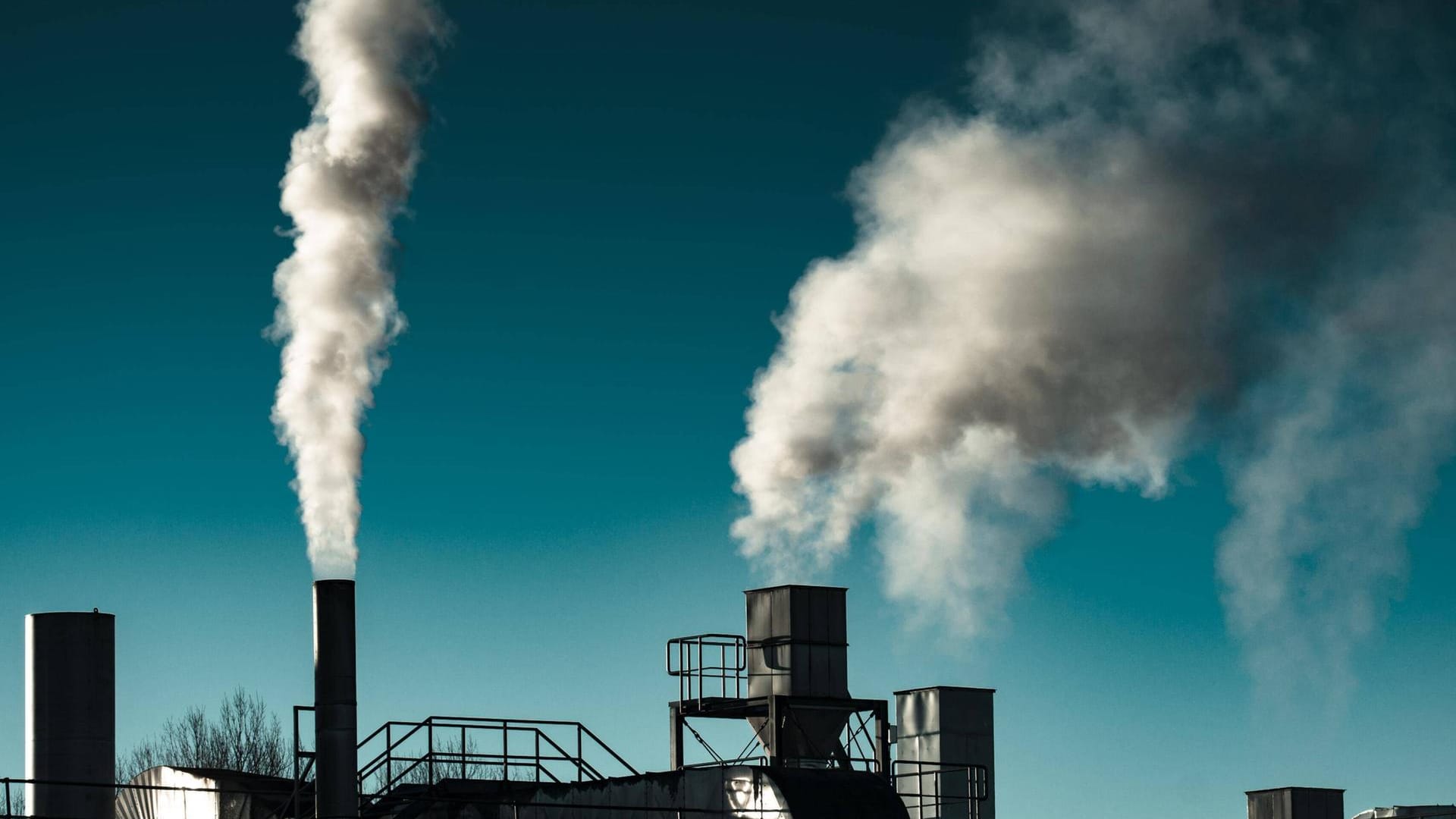 Fabrik mit rauchenden Schornsteinen (Symbolbild): In einer Chemiefabrik an der Grenze zu Österreich ist es zu einem Unfall gekommen.