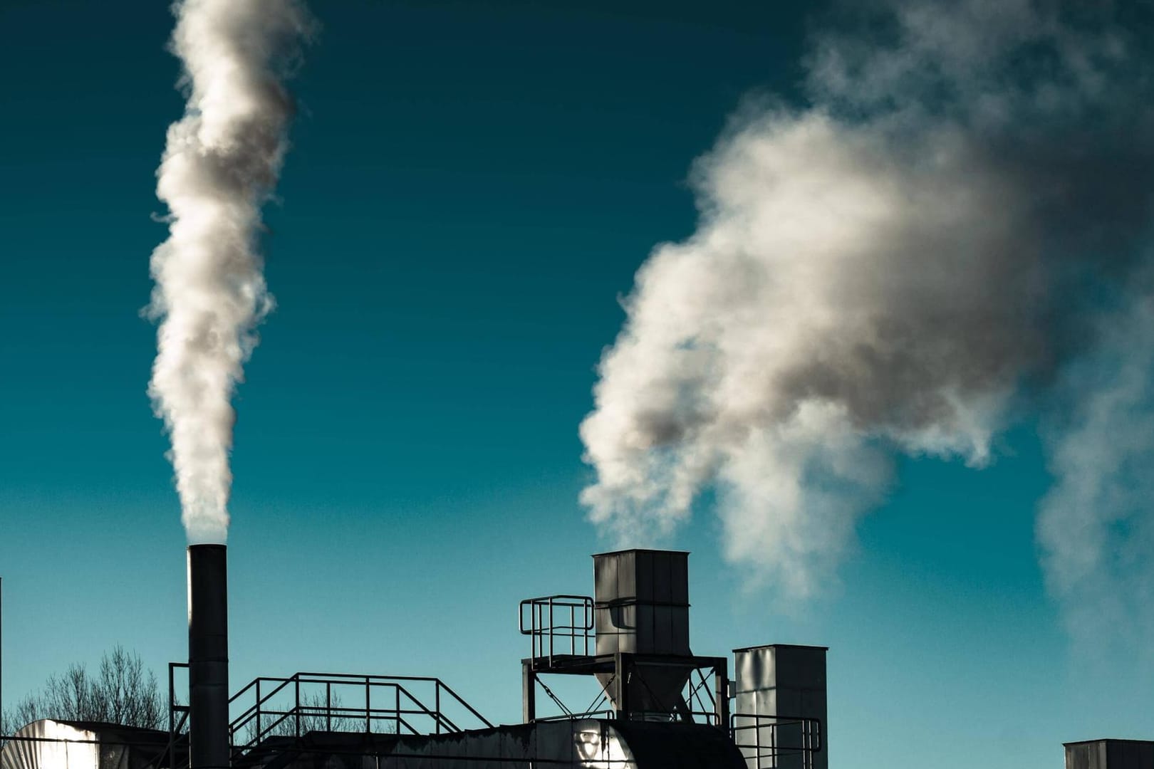 Fabrik mit rauchenden Schornsteinen (Symbolbild): In einer Chemiefabrik an der Grenze zu Österreich ist es zu einem Unfall gekommen.