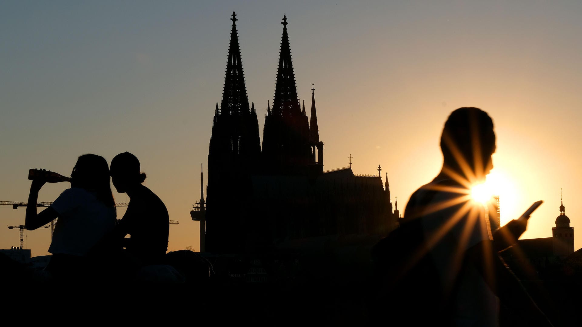 Menschen genießen im Sonnenuntergang am Rheinboulevard vor dem Dom die Abendstimmung: In Köln ist die Inzidenz auf knapp unter 40 gesunken. Menschen genießen im Sonnenuntergang am Rheinboulevard vor dem Dom die Abendstimmung: In Köln ist die Inzidenz auf knapp unter 40 gesunken.