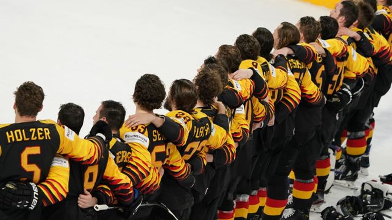 Das deutsche Eishockey-Nationalteam steht Arm in Arm auf dem Eis.