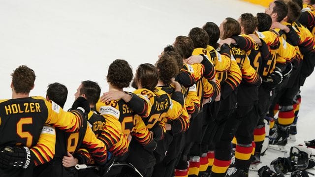 Das deutsche Eishockey-Nationalteam steht Arm in Arm auf dem Eis.