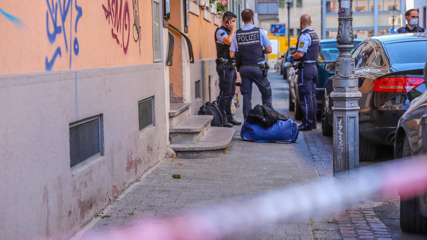 Polizisten stehen hinter einem Absperrband der Polizei am Tatort: In Karlsruhe ist eine Frau auf ihren Lebensgefährten losgegangen.