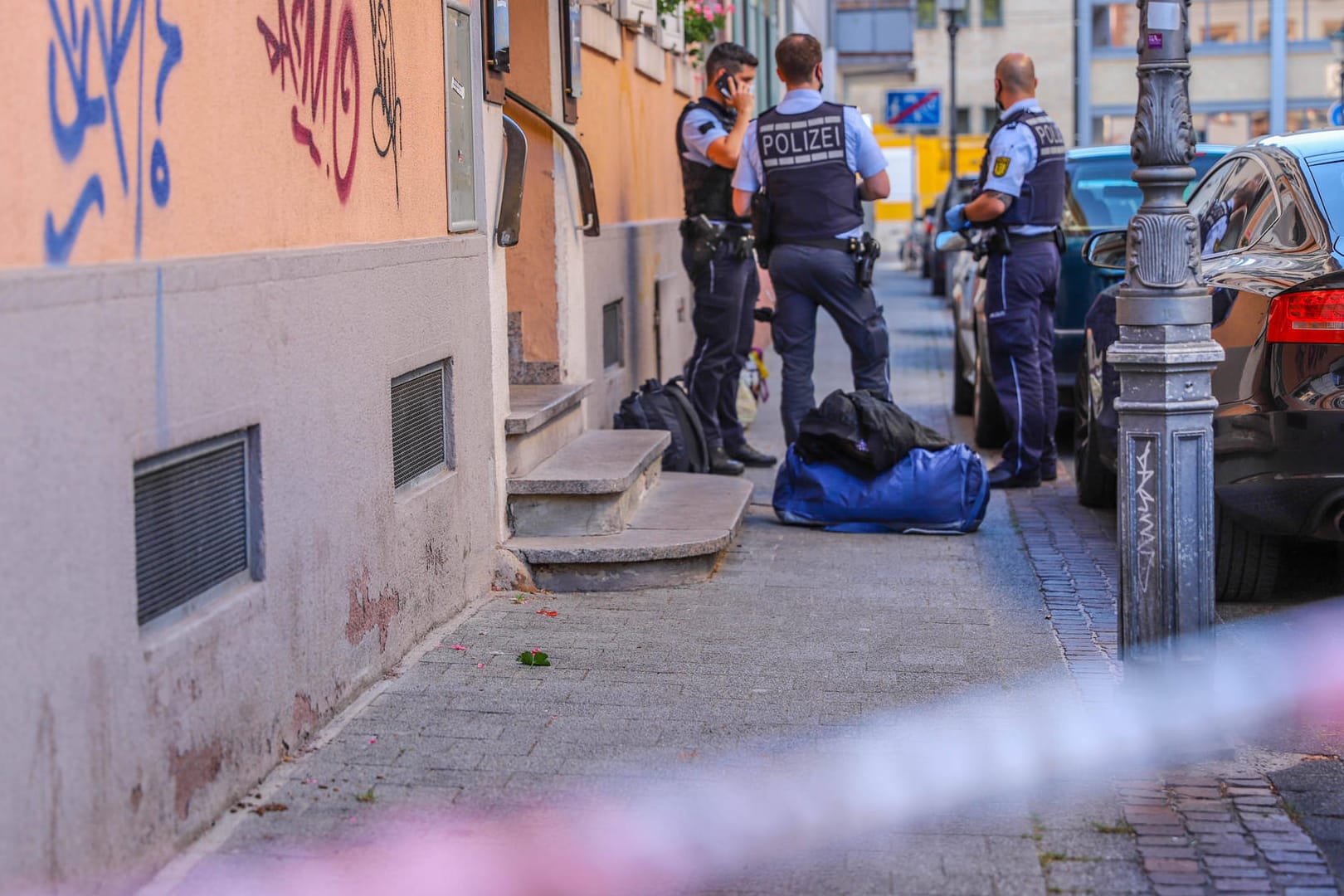 Polizisten stehen hinter einem Absperrband der Polizei am Tatort: In Karlsruhe ist eine Frau auf ihren Lebensgefährten losgegangen.