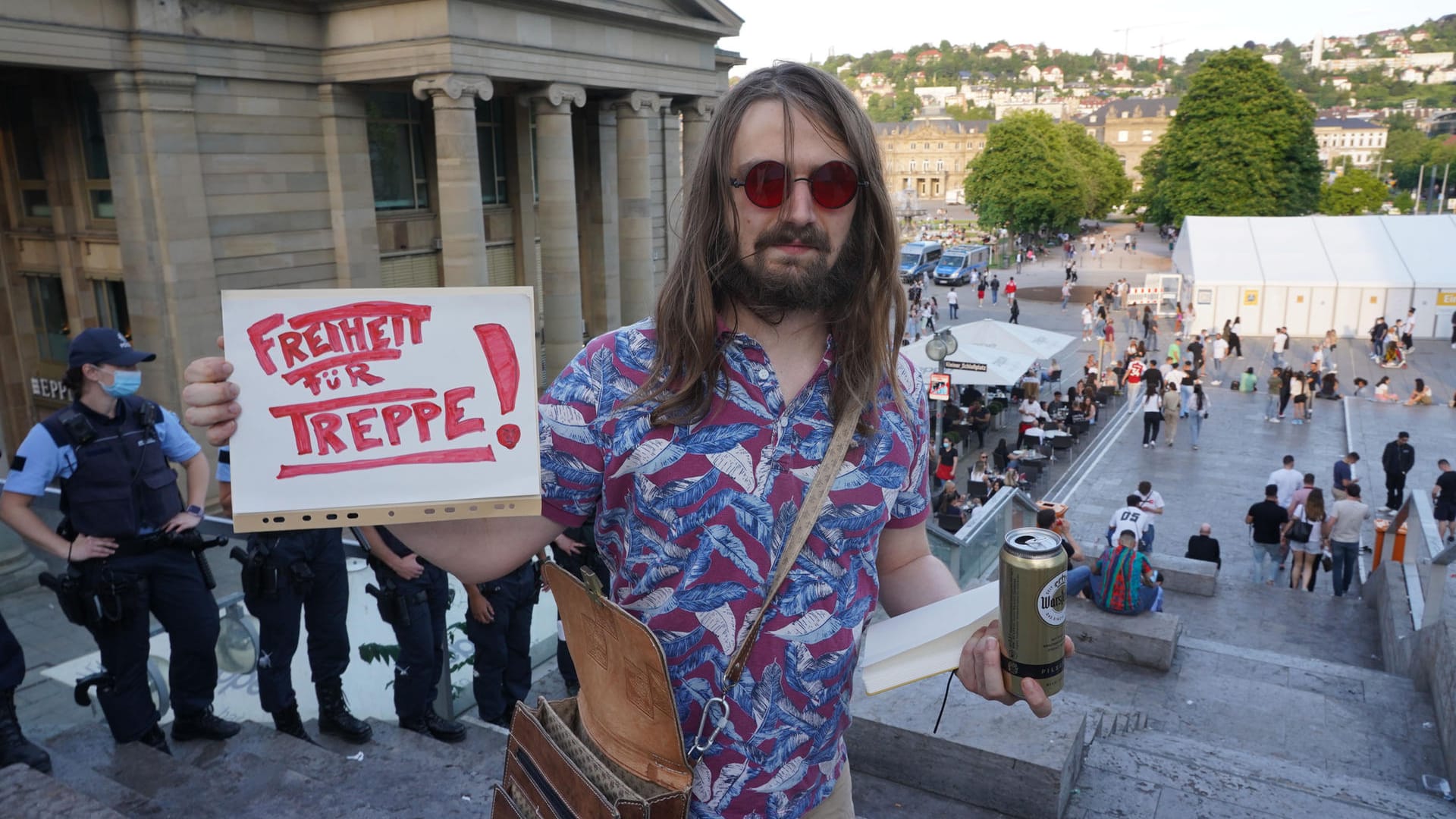 Ein Mann hält ein Schild mit der Aufschrift "Freiheit für Treppe": In Stuttgart wurde die bei Feiernden beliebte Freitreppe am Schlossplatz gesperrt. In den kommenden Tagen werden in der Landeshauptstadt auch berittene Polizei und Anti-Konfliktteams eingesetzt.