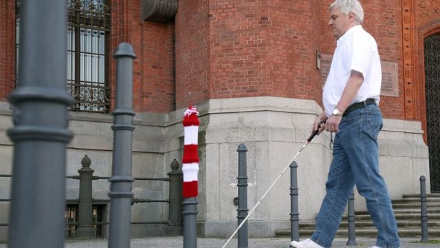 Ein sehbehinderter Mann vor einem Poller Ein sehbehinderter Mann vor einem Poller