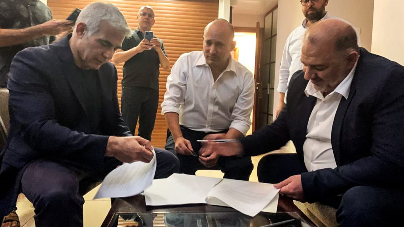 Jair Lapid, Naftali Bennett und Mansour Abbas beim Durchgehen der Koalitionspapiere: Gemeinsam mit fünf weiteren Parteien wollen die Politiker eine neue Regierungskoalition in Israel bilden.