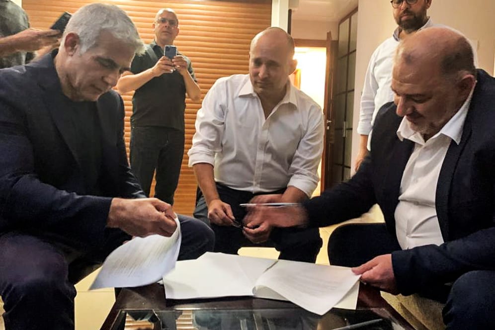 Jair Lapid, Naftali Bennett und Mansour Abbas beim Durchgehen der Koalitionspapiere: Gemeinsam mit fünf weiteren Parteien wollen die Politiker eine neue Regierungskoalition in Israel bilden.